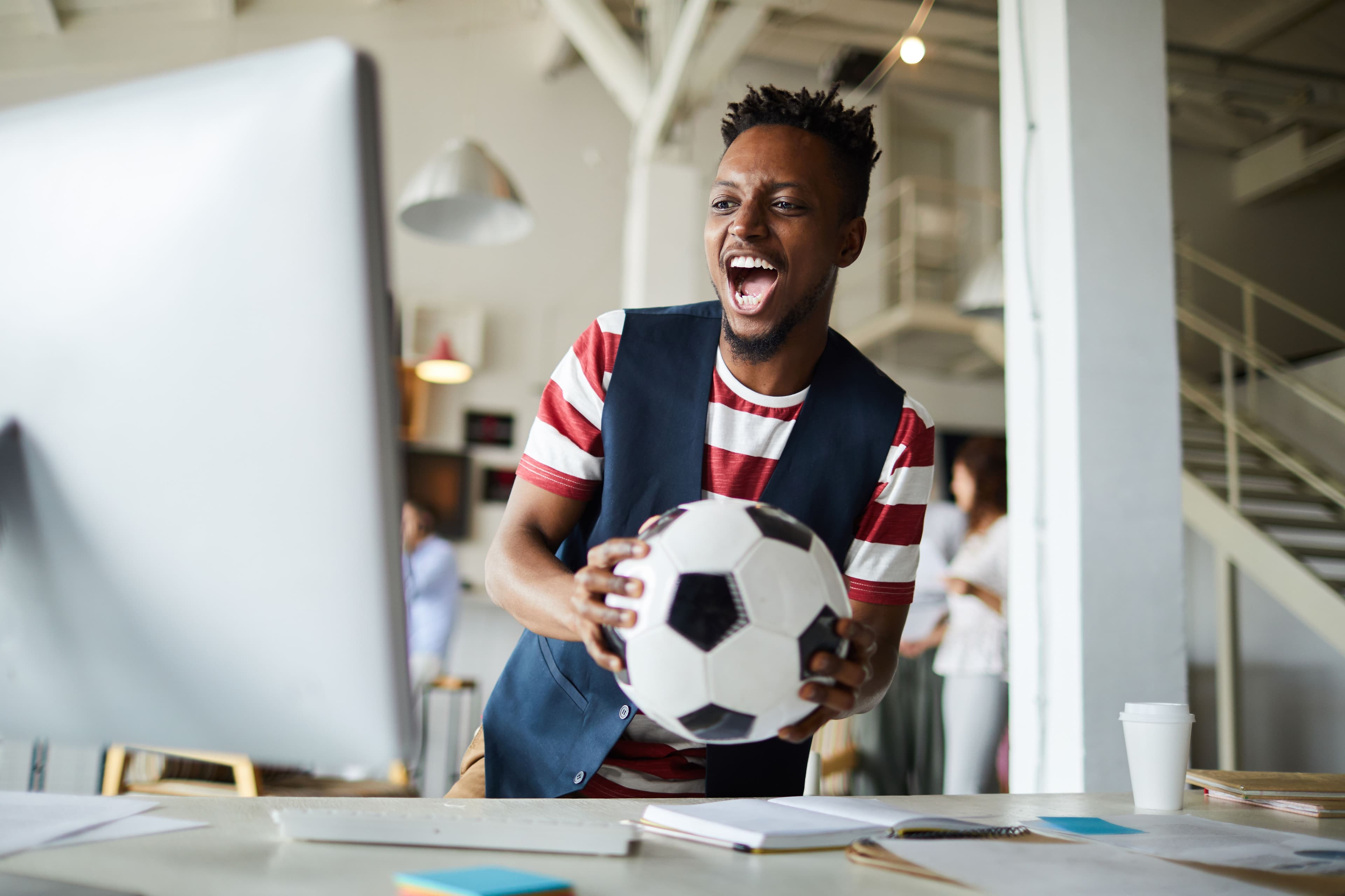 Ragazzo con pallone da calcio in mano che studia per diventare Football Manager